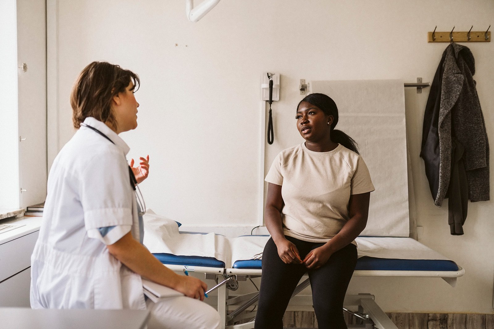 En kvinna sitter på en sjukhusbrits och talar med en läkare.